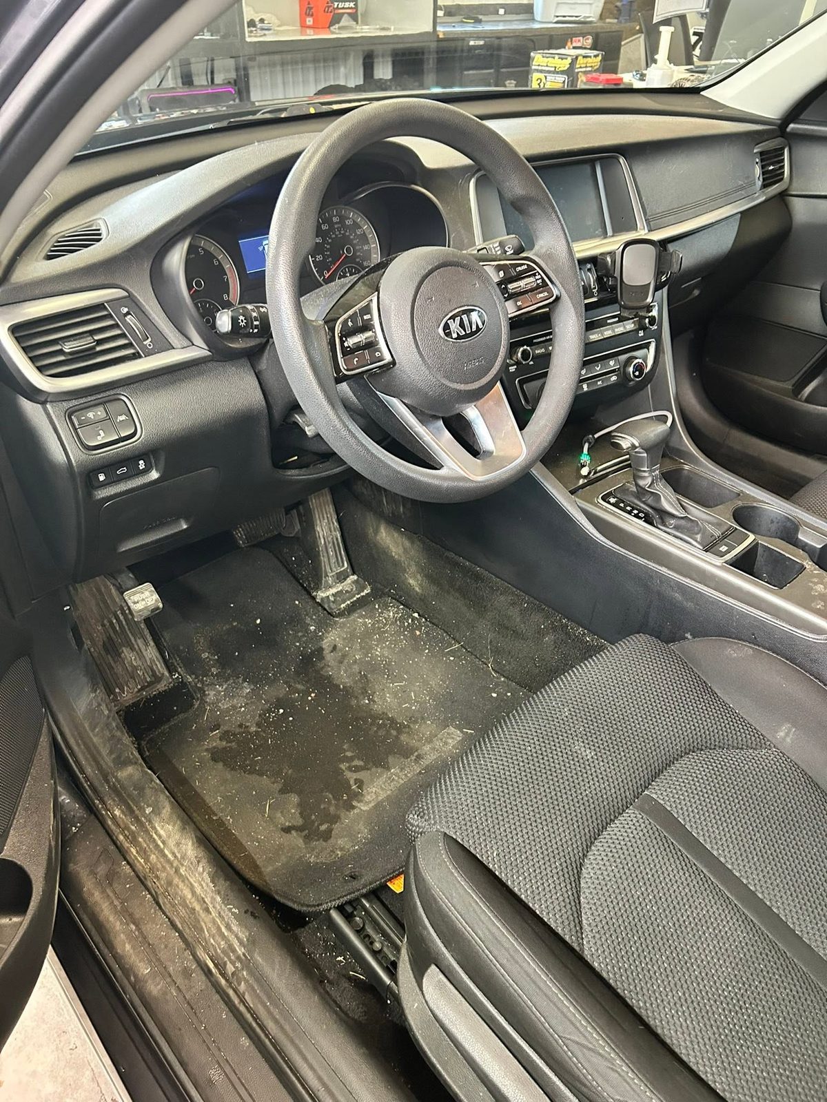 Kia Optima driver's side before detailing: carpet caked with mud, salt, and debris
